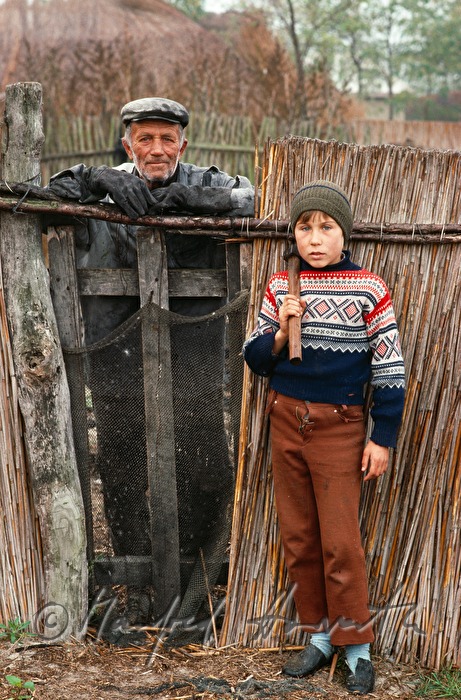 worker and lad in front of a reed fence