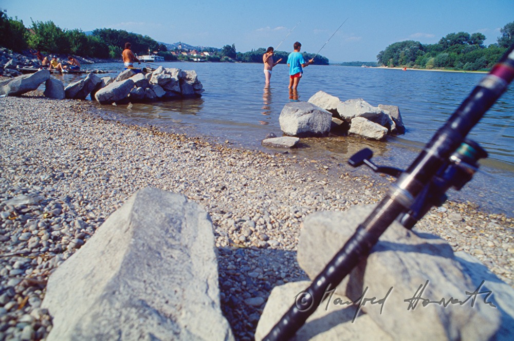 fishermen and bathing guests on the rivershore of the Danube