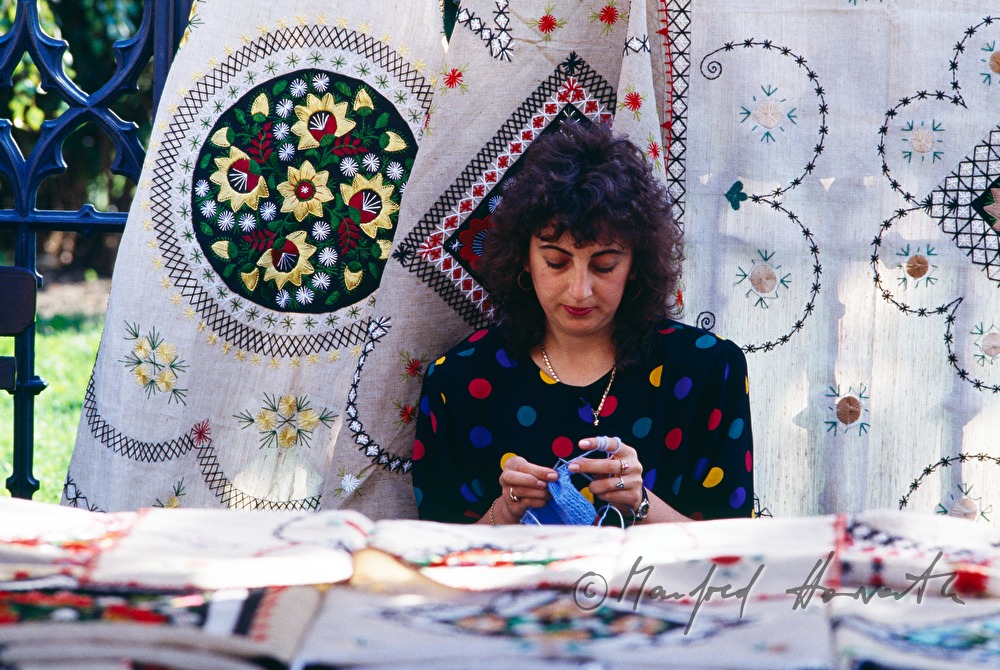 saleslady knitting in her stand with tablecloth