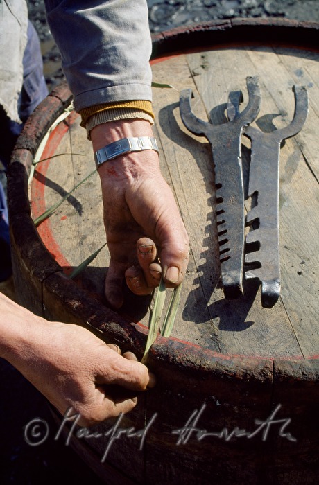 cooper tightens a barrel with bulrushes