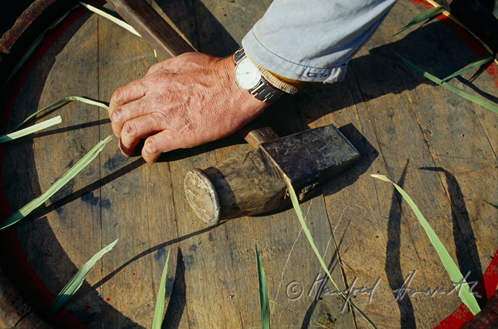 cooper tightens a barrel with bulrushes