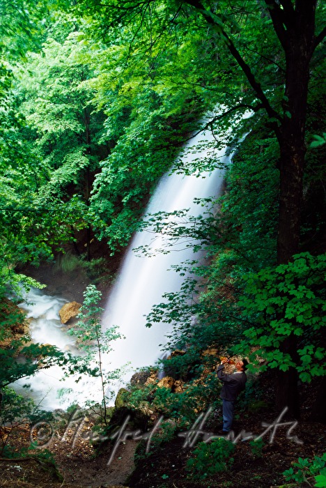 hiker drinks near a waterfall