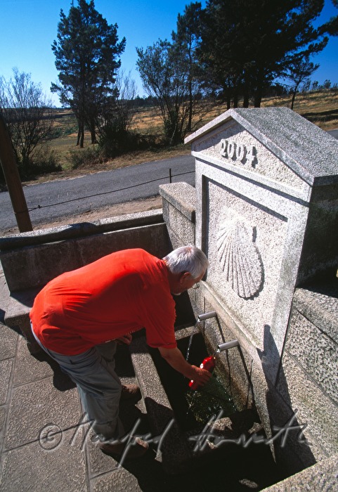 pilgrim fills his water bottle at a fountain
