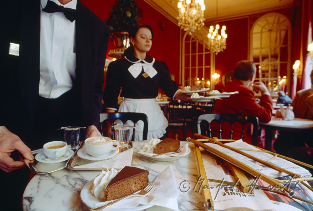 waiter serves Sachertorte and a cafe