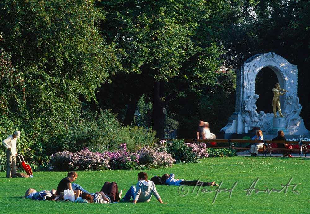 sunworshippers on the lawn near the statue of Johann Strauss