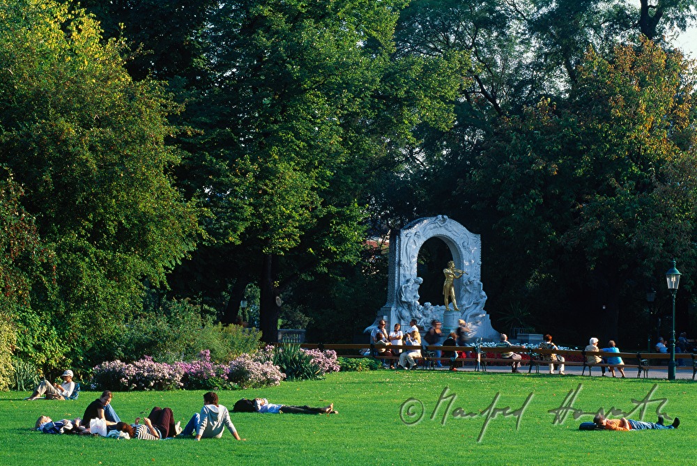sunworshippers on the lawn near the statue of Johann Strauss