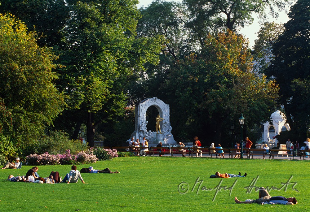 sunworshippers on the lawn near the statue of Johann Strauss