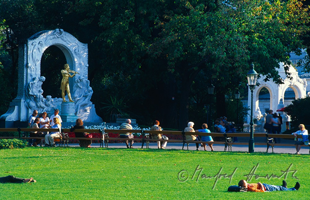 sunworshippers on the lawn near the statue of Johann Strauss