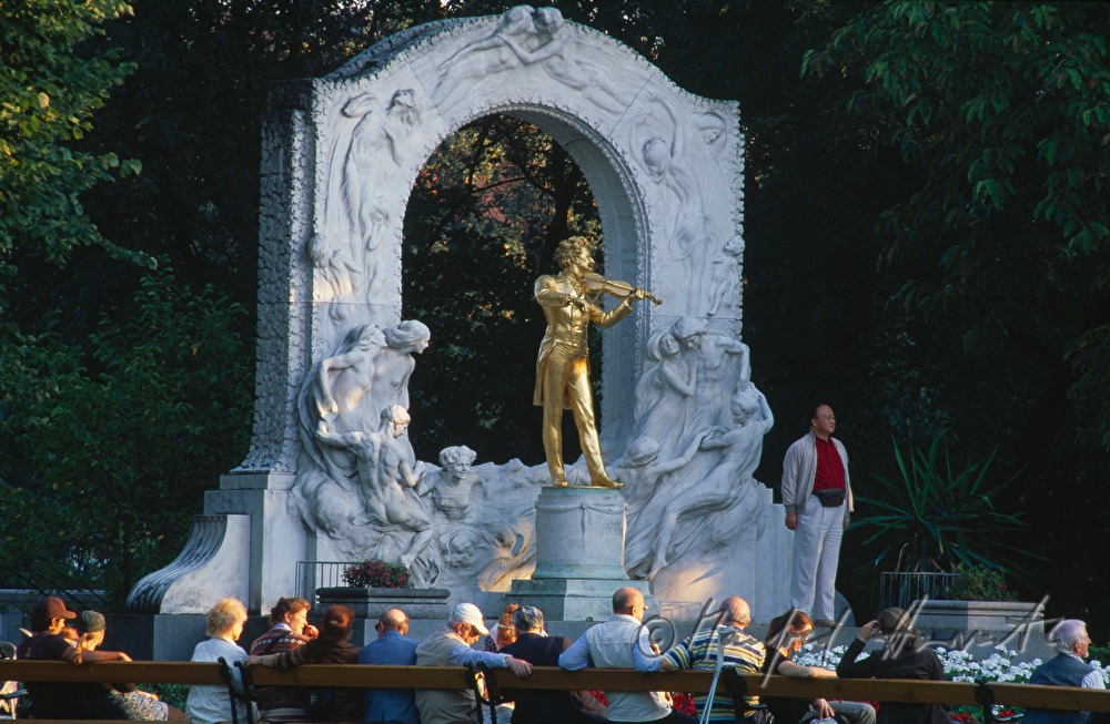 sunworshippers on the lawn near the statue of Johann Strauss