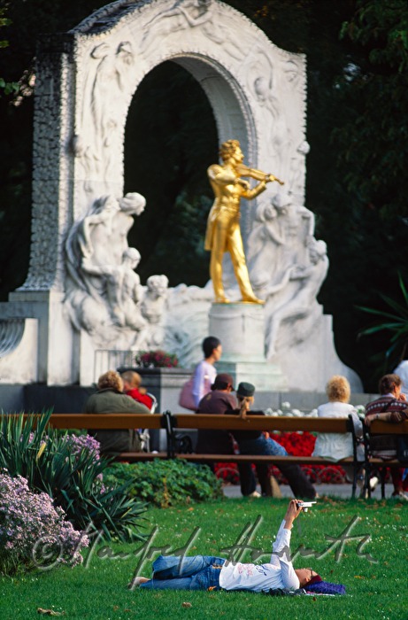 sunworshippers on the lawn near the statue of Johann Strauss