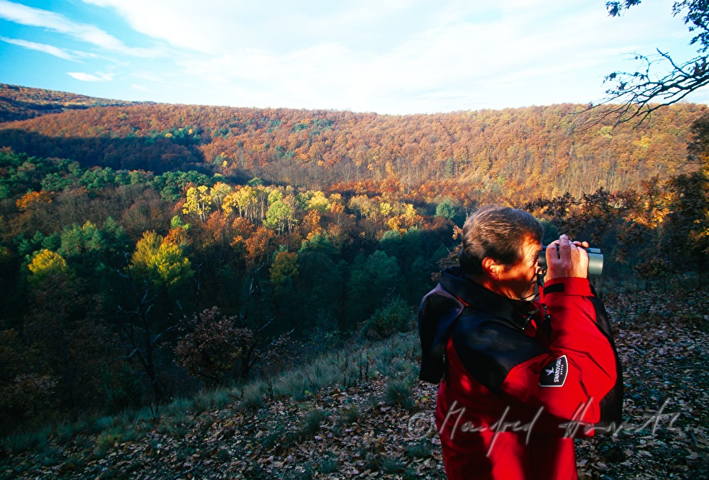 biologist with binoculars on the shore of the Pinka River