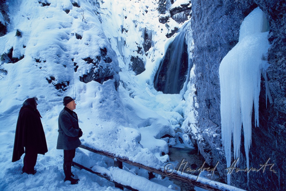 pilgrims pray near a frozen waterfall