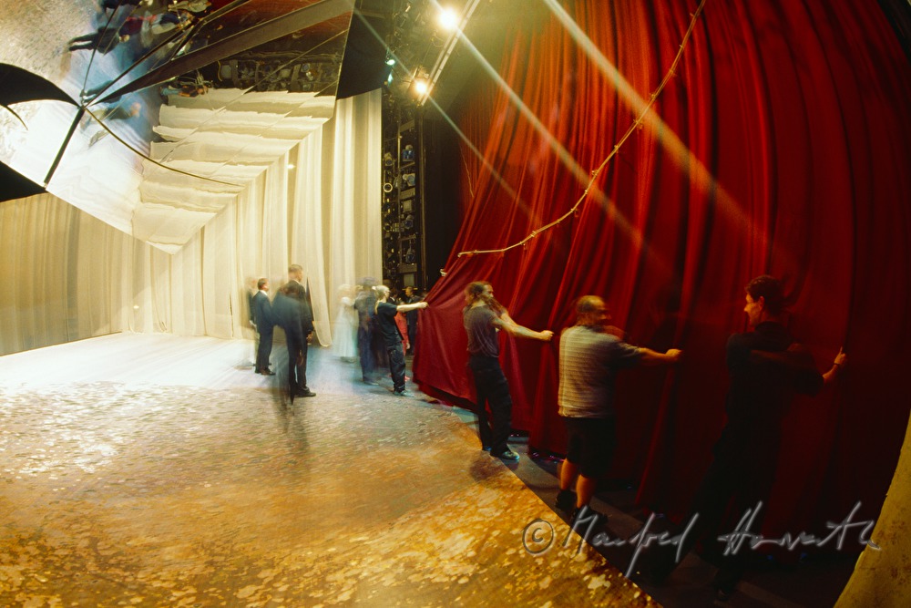 stage workers close the red curtain