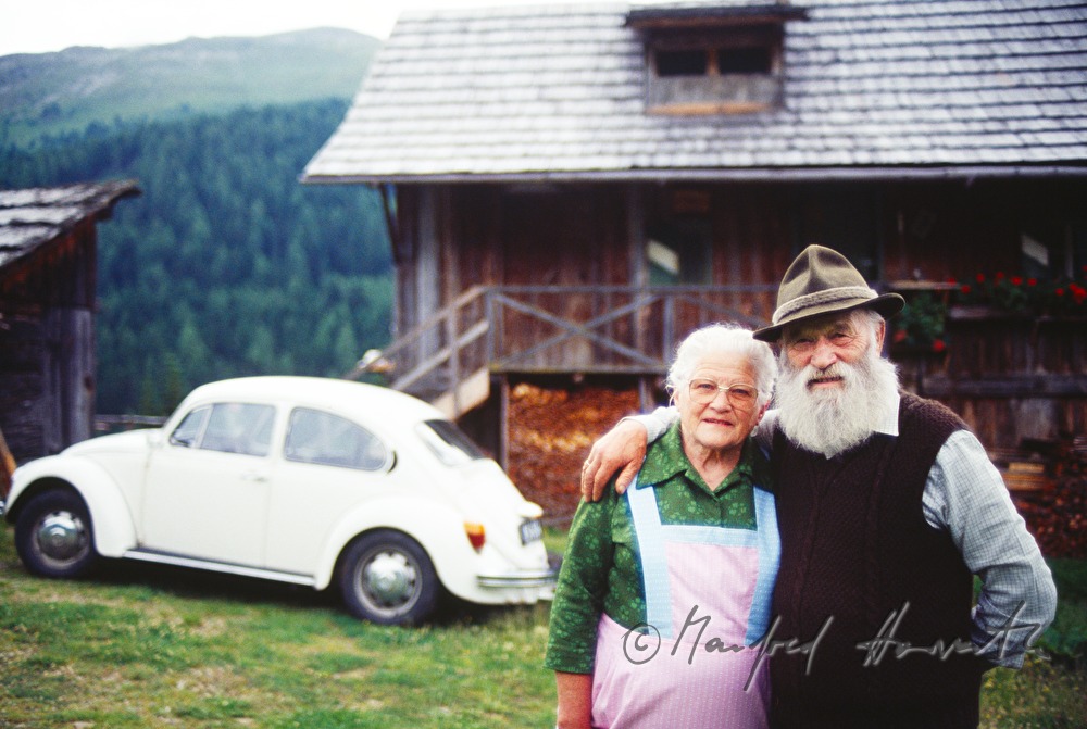 elderly couple in front of their alpine house