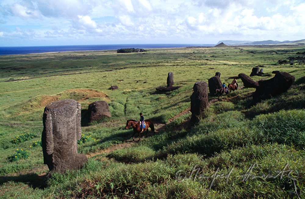two riders passing Moai statues