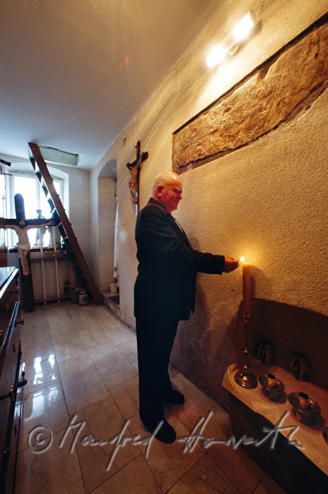priest lighting a candle in the sacristy