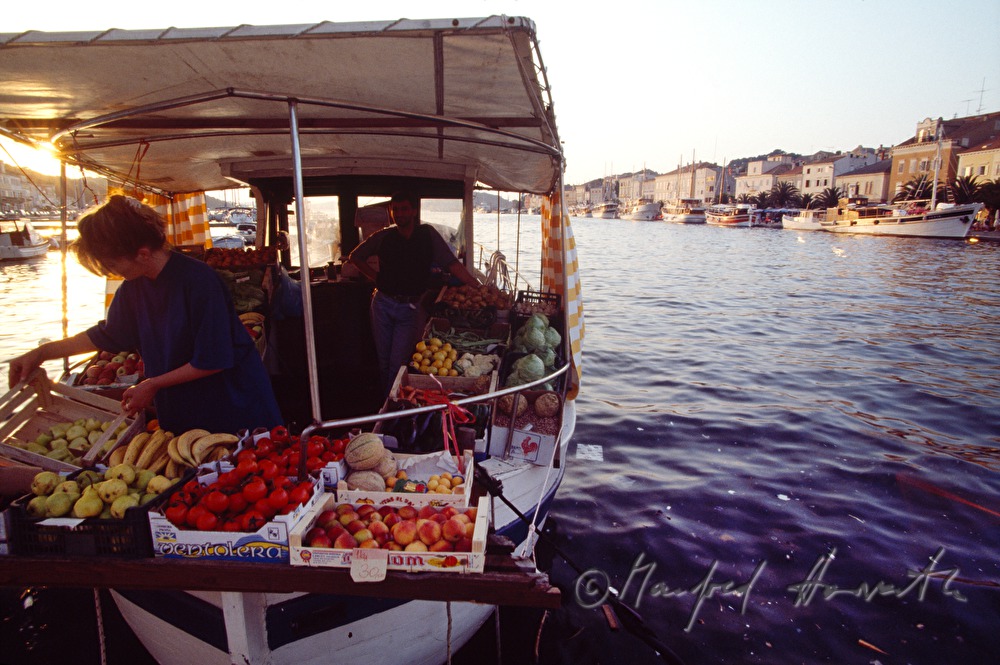 fruit and vegetable are sold on a boat in the harbour