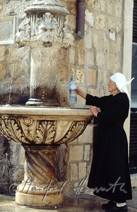 woman takes water of a fountain