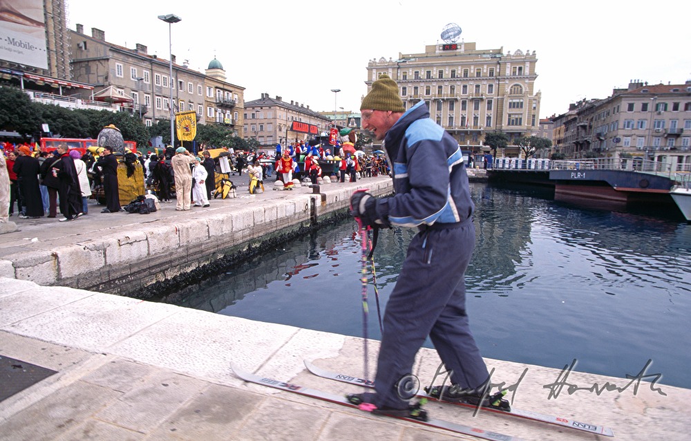 Participant of the carnival dressed up as a skier at the harbour.