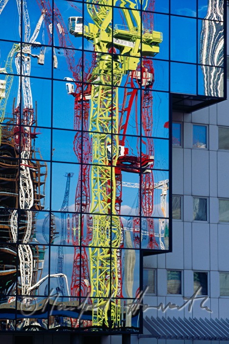 dockside cranes reflect in a glass pane