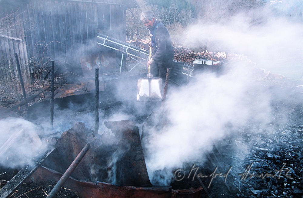 charcoal maker Stefan Zechberger on a pile of charcoal