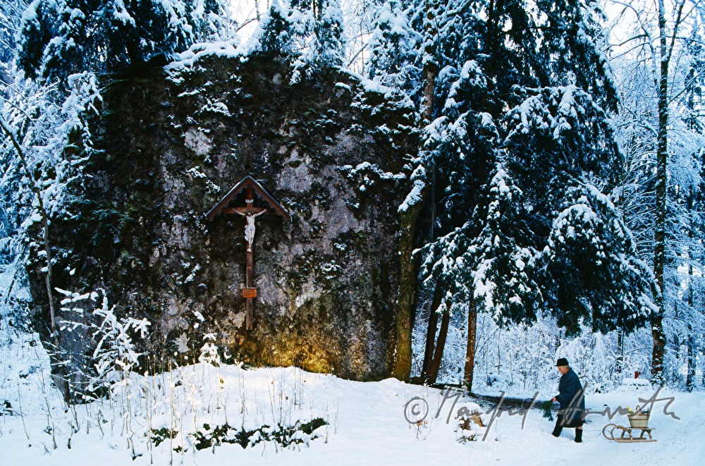 Christian wayside cross and woman with sledge