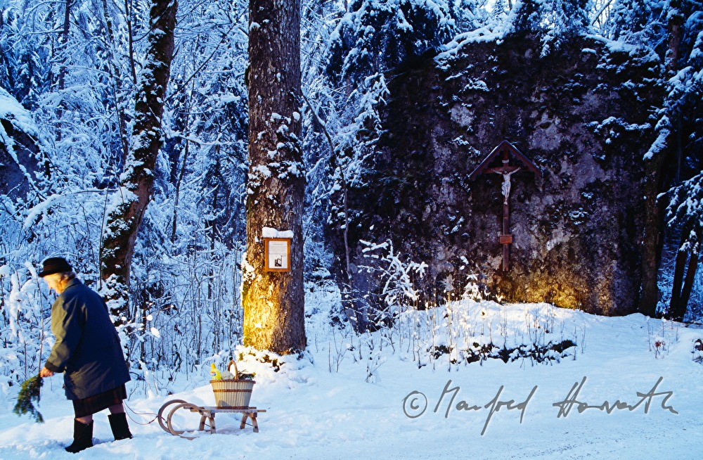 Christian wayside cross and woman with sledge