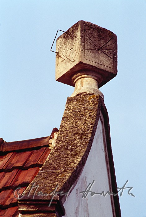 cube-shaped sundial on the roof of a house