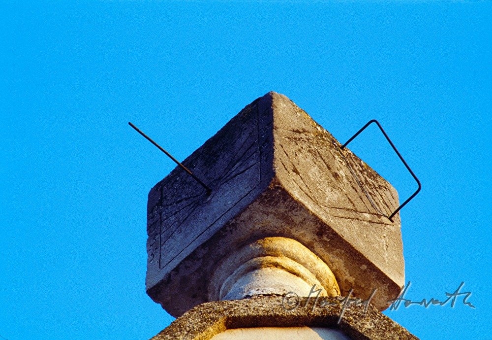 cube-shaped sundial on the roof of a house