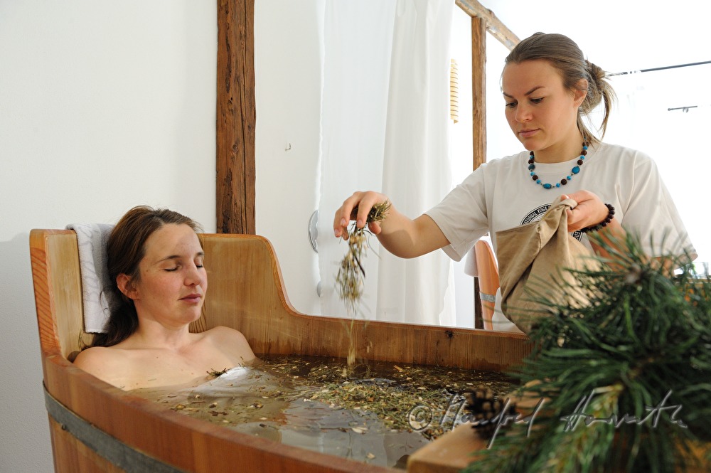 woman takes a wellness dwarf pine bath in a wooden tub