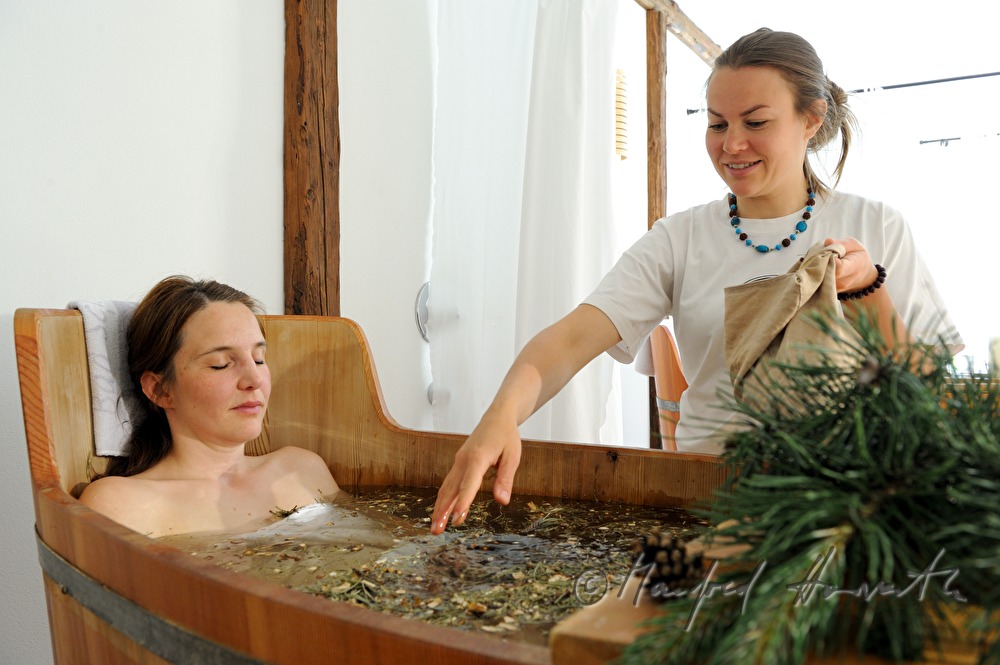 woman takes a wellness dwarf pine bath in a wooden tub