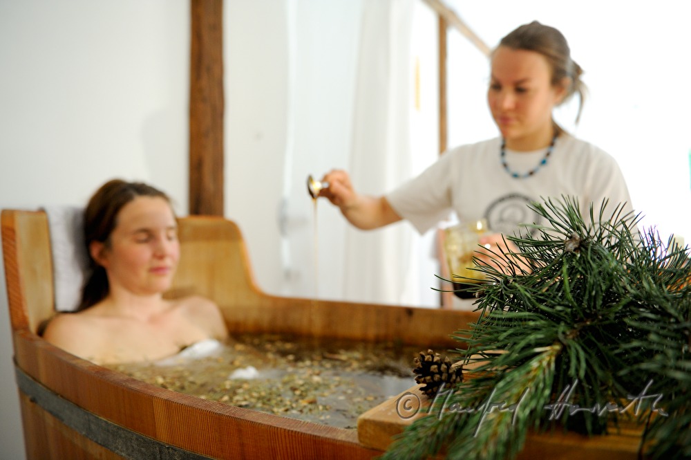 woman takes a wellness dwarf pine bath in a wooden tub