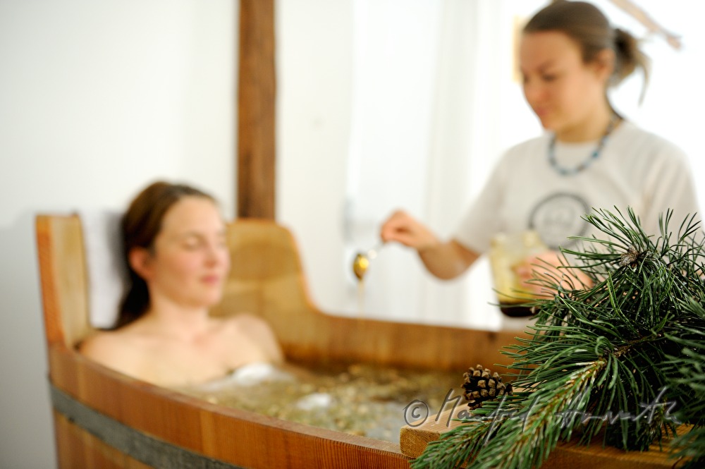 woman takes a wellness dwarf pine bath in a wooden tub