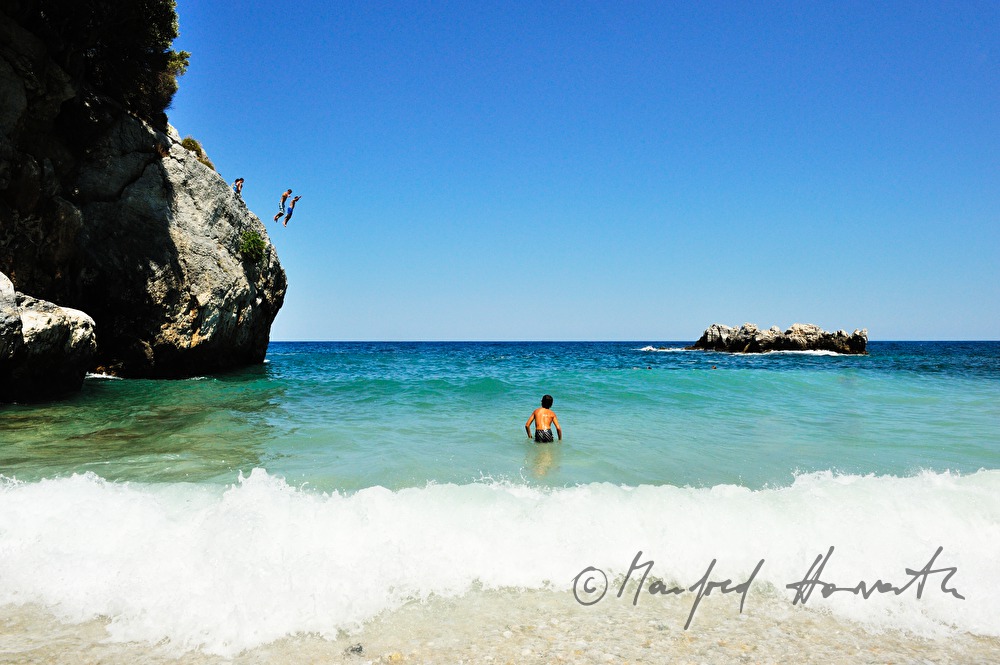 kids jump from a rock into the ocean