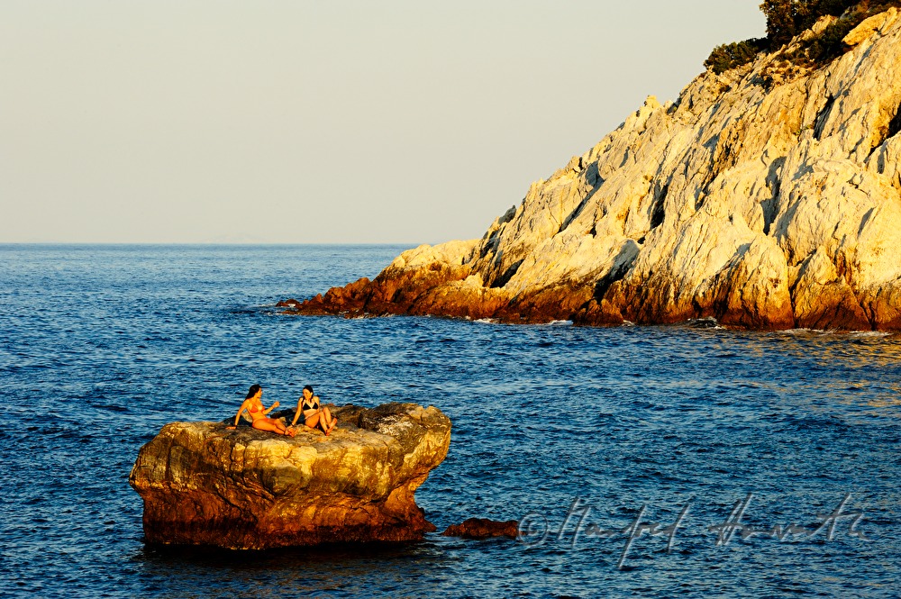 two women sunbath on a tiny island