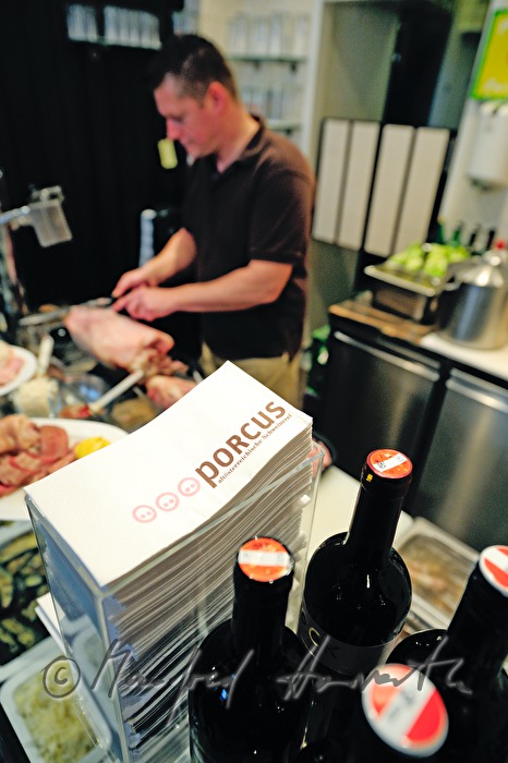 Restaurant Porcus, the chef cuts meat from a big ham
