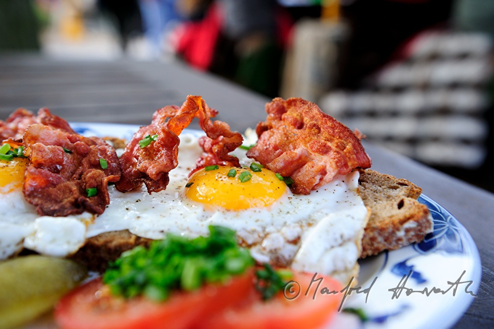 fried egg on dark bread with fried bacon