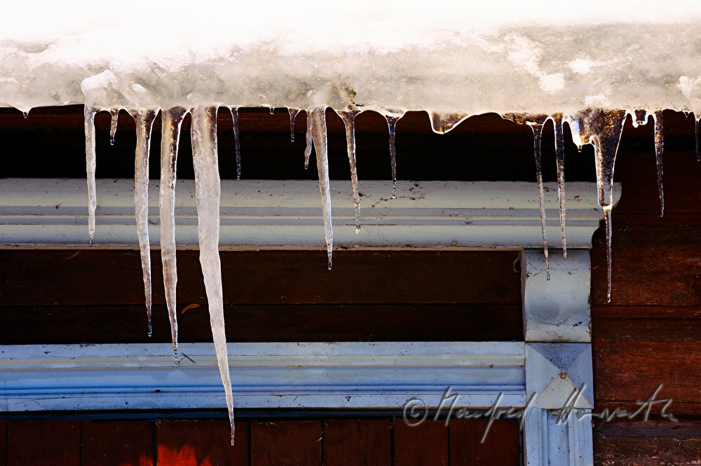 icicles on the roof of a wooden house