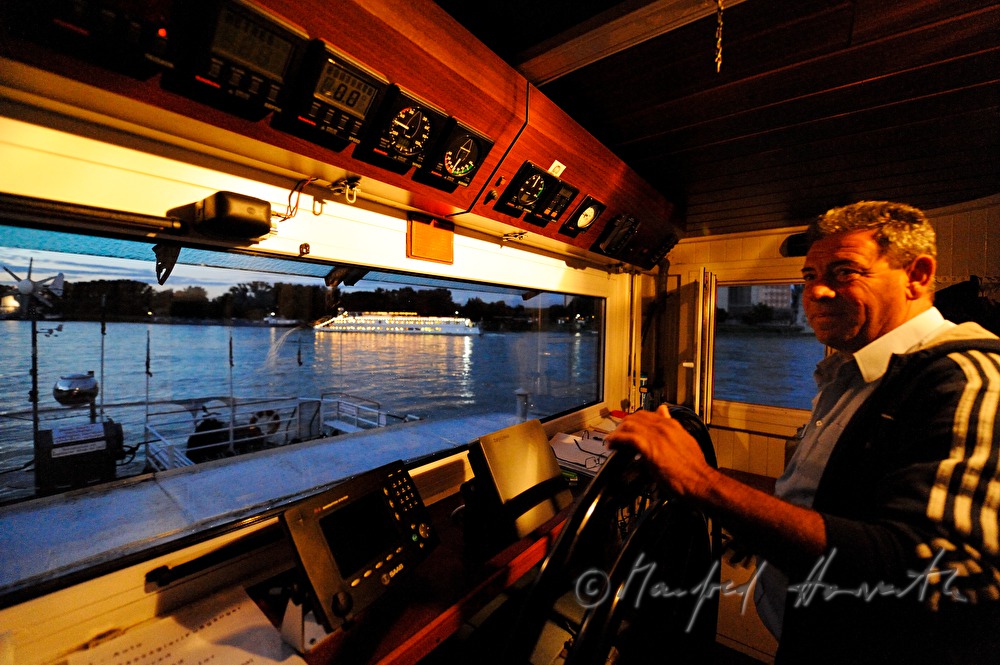 ferryman on the steering wheel of his boat
