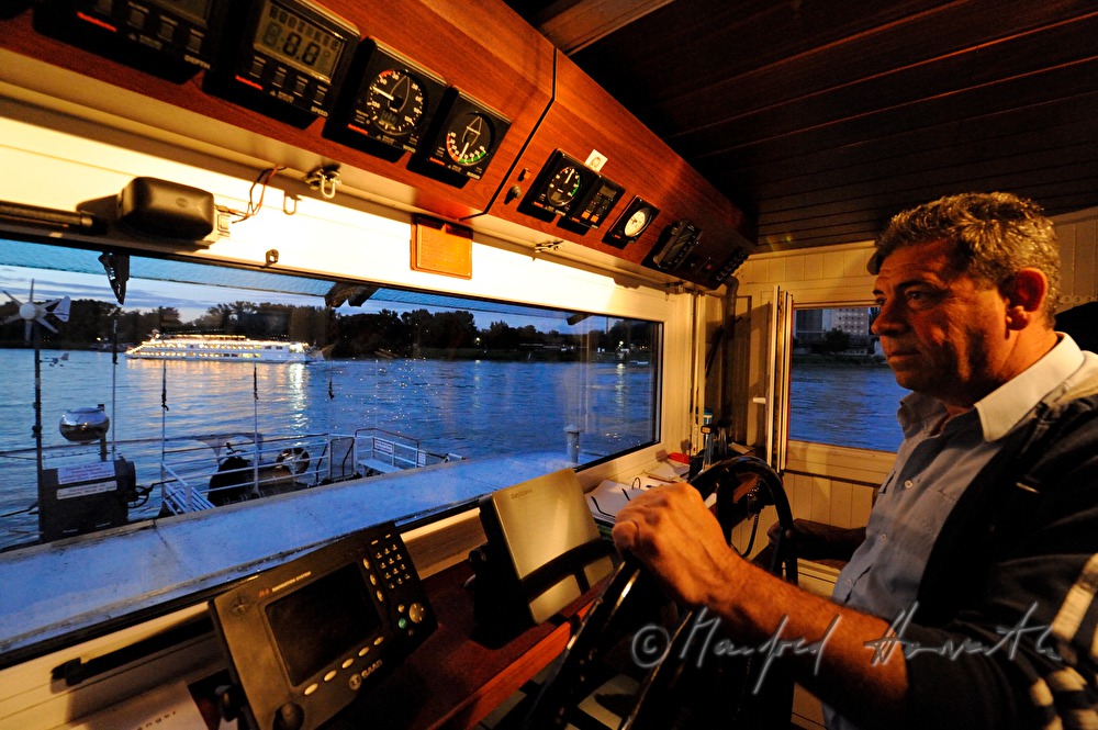 ferryman on the steering wheel of his boat