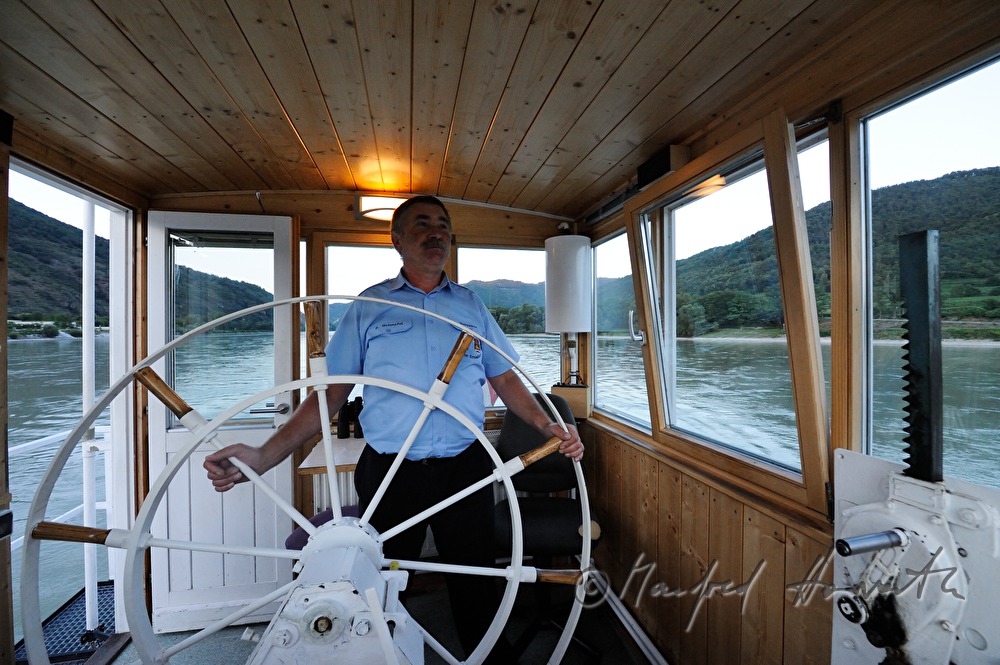ferryman on the steering wheel of his boat