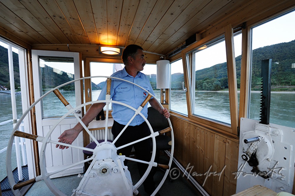 ferryman on the steering wheel of his boat