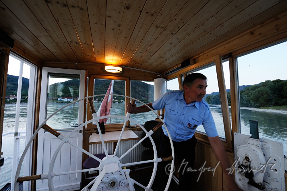 ferryman on the steering wheel of his boat