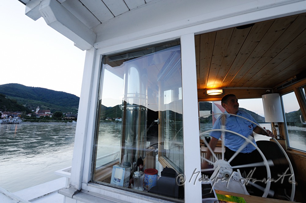 ferryman on the steering wheel of his boat