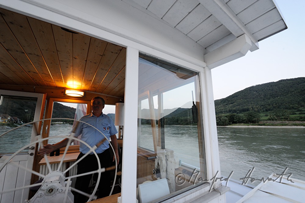 ferryman on the steering wheel of his boat