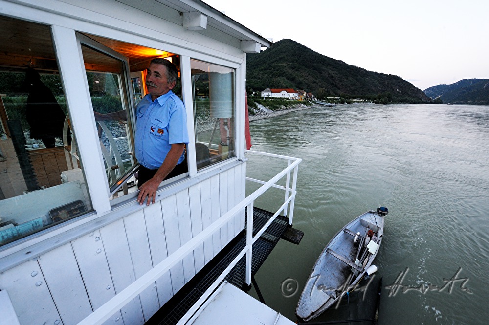 ferryman on the steering wheel of his boat