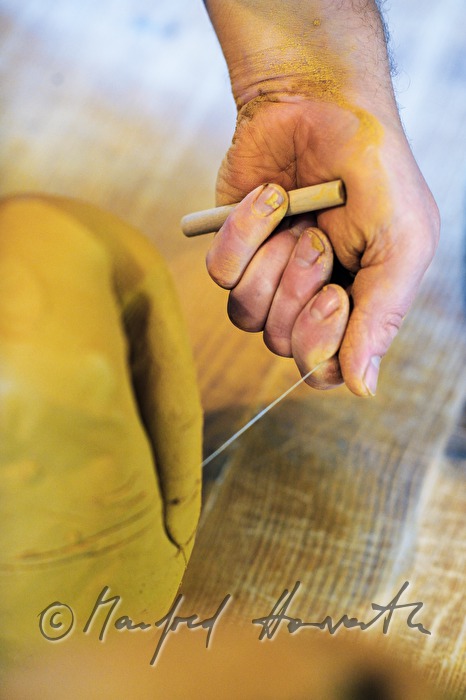 potter Joef Wieser cuts clay with a tring