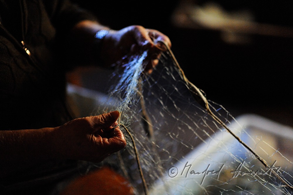 fisherman repairing nets in the fisherman's cottage