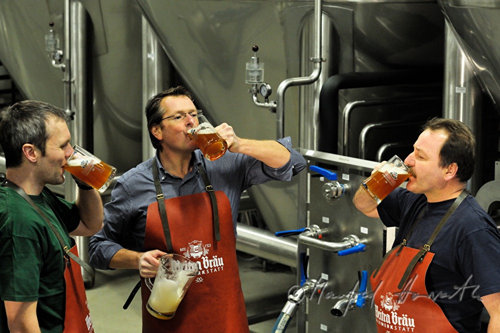 master brewer and workers tasting beer in the cellar