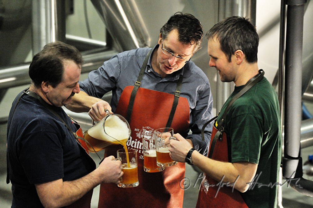 master brewer and workers tasting beer in the cellar